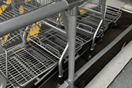 A t-shaped metal pipe sleeve connector in a trolley bay, used to protect shopping trolleys.